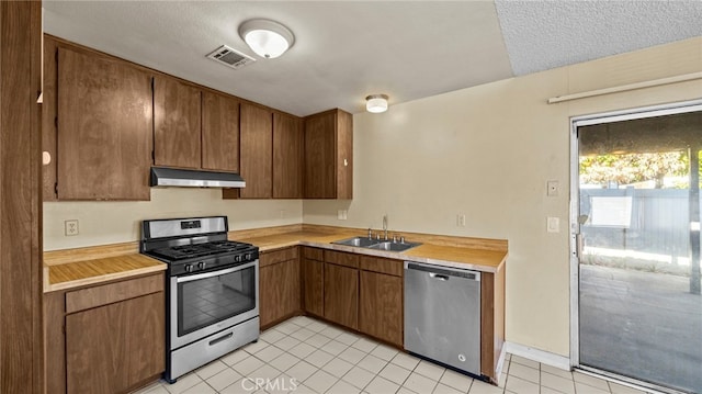 kitchen featuring appliances with stainless steel finishes, sink, a textured ceiling, and light tile patterned flooring