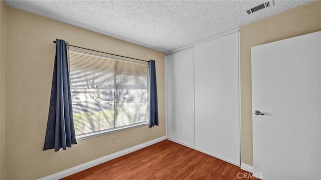 empty room with a textured ceiling and wood-type flooring