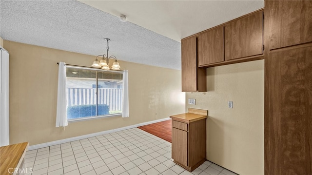 kitchen featuring wood counters, light tile patterned floors, a notable chandelier, hanging light fixtures, and a textured ceiling