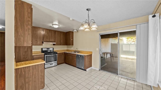 kitchen featuring a textured ceiling, stainless steel appliances, hanging light fixtures, and sink