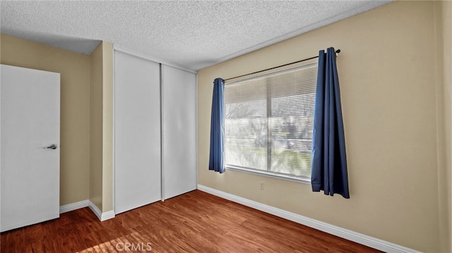 unfurnished bedroom with a closet, a textured ceiling, and hardwood / wood-style floors