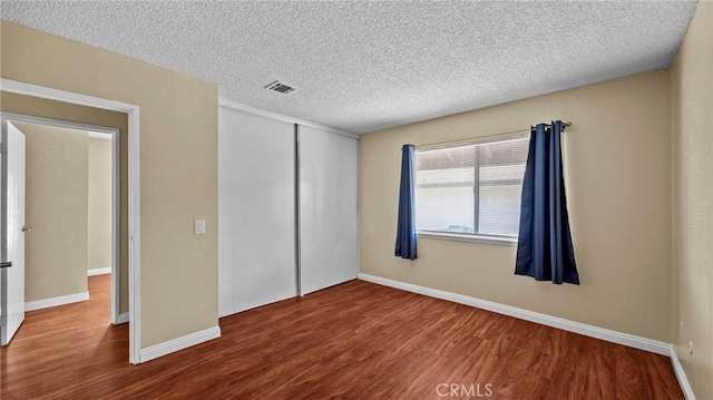 unfurnished bedroom featuring hardwood / wood-style floors, a closet, and a textured ceiling