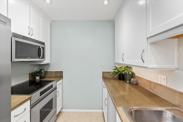 kitchen with white cabinets, light tile patterned flooring, and stainless steel appliances