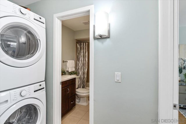 laundry area featuring light tile patterned floors and stacked washer and clothes dryer