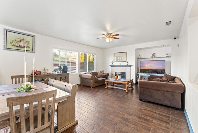 living room featuring ceiling fan, dark hardwood / wood-style flooring, and a tile fireplace