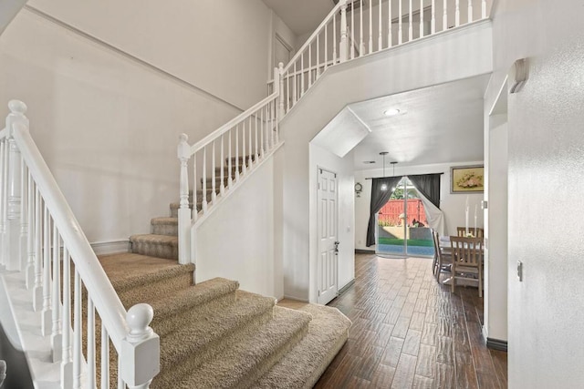 stairs with wood-type flooring and a towering ceiling