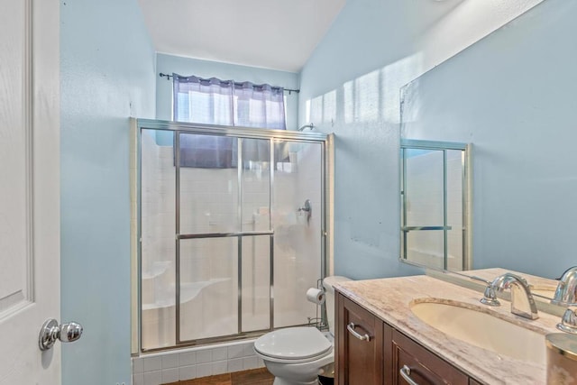 bathroom with hardwood / wood-style floors, vaulted ceiling, toilet, a shower with door, and vanity