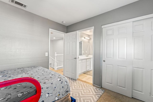 bedroom featuring ensuite bathroom, light colored carpet, sink, and a closet