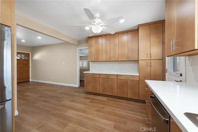 kitchen featuring decorative backsplash, ceiling fan, stainless steel appliances, and light wood-type flooring