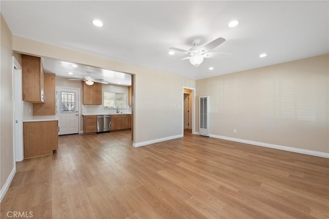 unfurnished living room with ceiling fan, sink, and light hardwood / wood-style floors