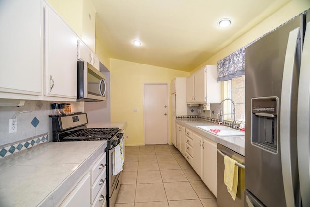 kitchen featuring lofted ceiling, sink, light tile patterned flooring, white cabinetry, and appliances with stainless steel finishes