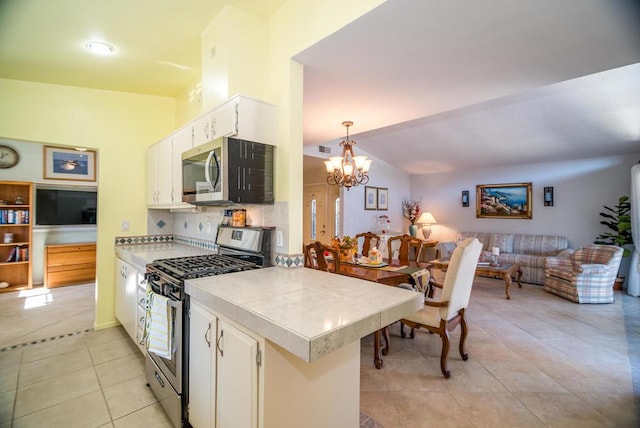 kitchen featuring white cabinets, decorative light fixtures, stainless steel appliances, kitchen peninsula, and light tile patterned floors