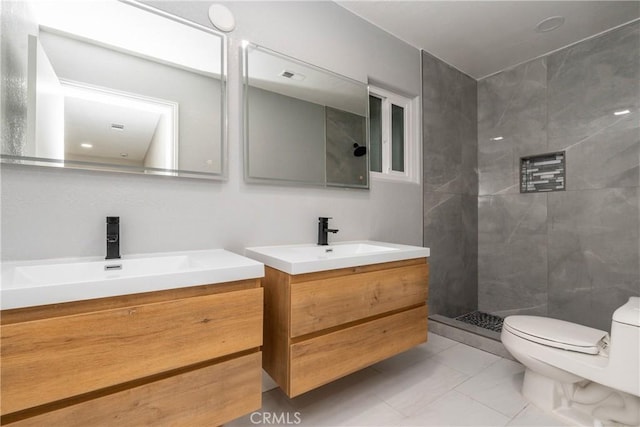 bathroom with a tile shower, vanity, and toilet