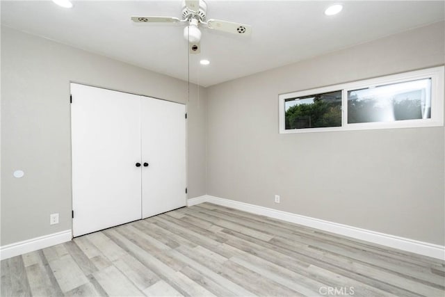 unfurnished bedroom with ceiling fan, a closet, and light wood-type flooring