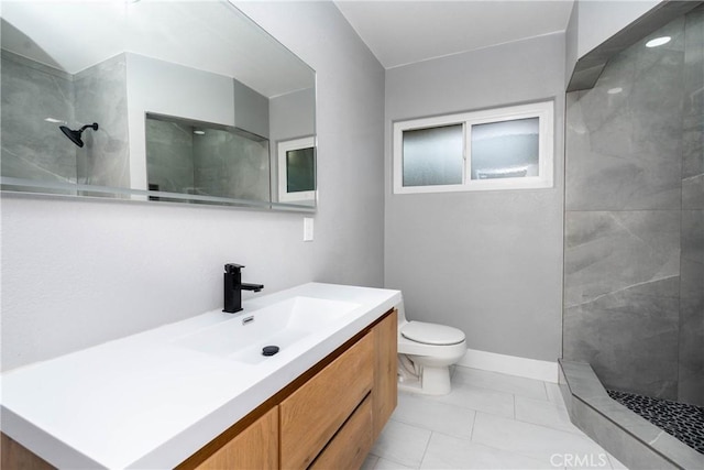 bathroom featuring tile patterned flooring, vanity, toilet, and tiled shower