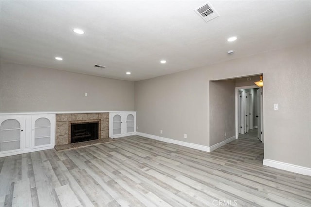 unfurnished living room featuring light hardwood / wood-style floors and a tile fireplace