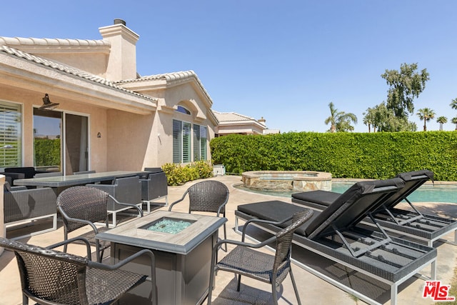 view of patio featuring a swimming pool with hot tub and a fire pit