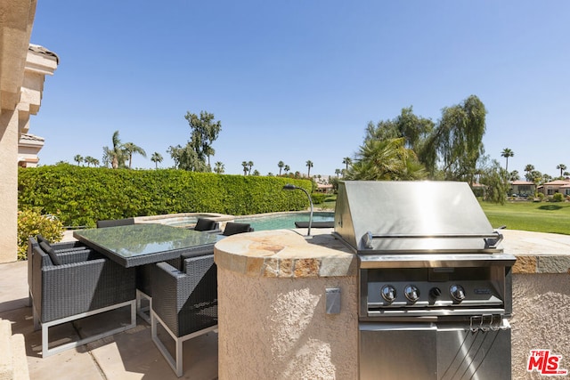 view of patio with a fenced in pool and area for grilling