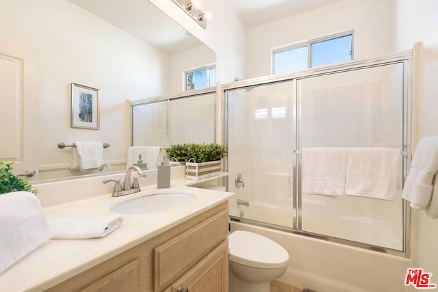 full bathroom featuring vanity, enclosed tub / shower combo, and toilet