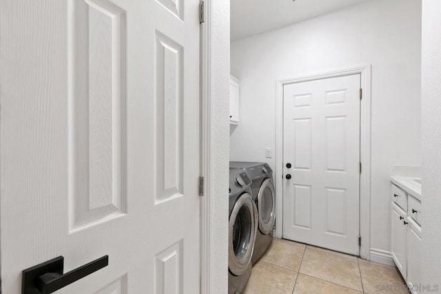 clothes washing area featuring cabinets, separate washer and dryer, and light tile patterned flooring