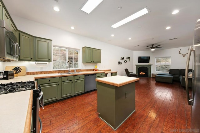 kitchen with sink, a center island, dark wood-type flooring, appliances with stainless steel finishes, and green cabinetry