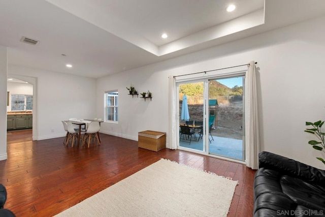 interior space with dark wood-type flooring, a wealth of natural light, and a tray ceiling