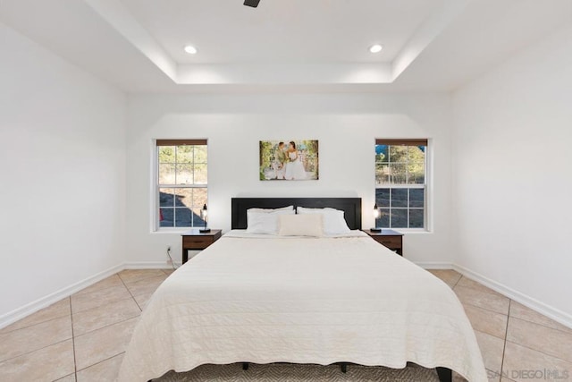 bedroom with a tray ceiling, multiple windows, and light tile patterned flooring