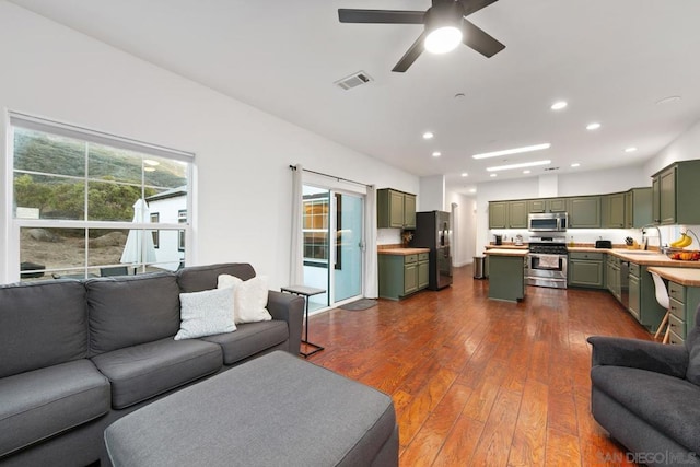 living room with dark hardwood / wood-style flooring, ceiling fan, and sink