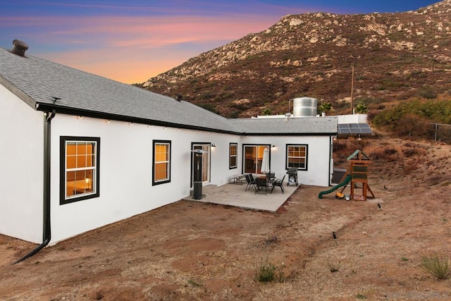 back house at dusk with a mountain view and a patio