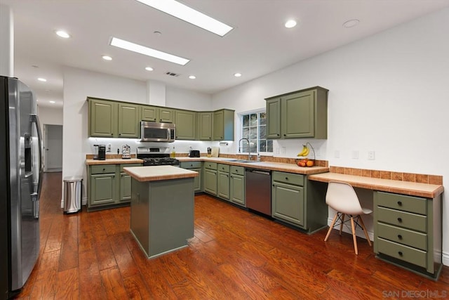 kitchen with sink, dark wood-type flooring, stainless steel appliances, green cabinets, and a kitchen island