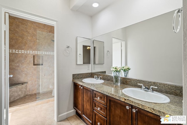 bathroom with toilet, vanity, tile patterned floors, and tiled shower