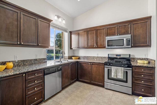 kitchen featuring appliances with stainless steel finishes, lofted ceiling, dark brown cabinets, and sink