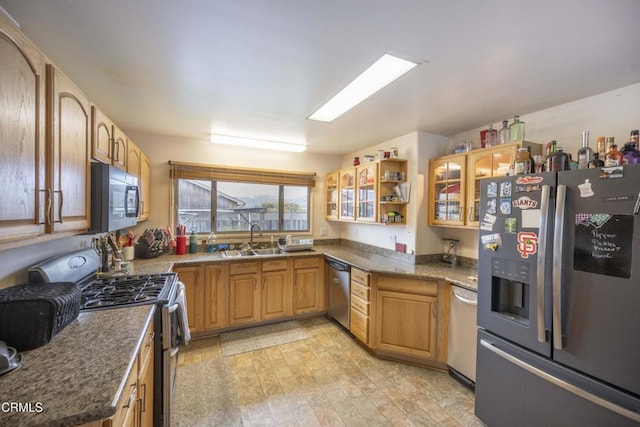 kitchen featuring dark stone countertops, sink, stainless steel appliances, and light hardwood / wood-style floors