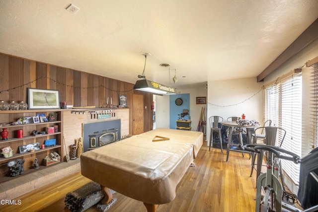 playroom featuring a textured ceiling, wooden walls, billiards, hardwood / wood-style floors, and a wood stove