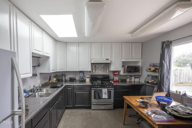 kitchen featuring appliances with stainless steel finishes, a skylight, white cabinetry, and sink