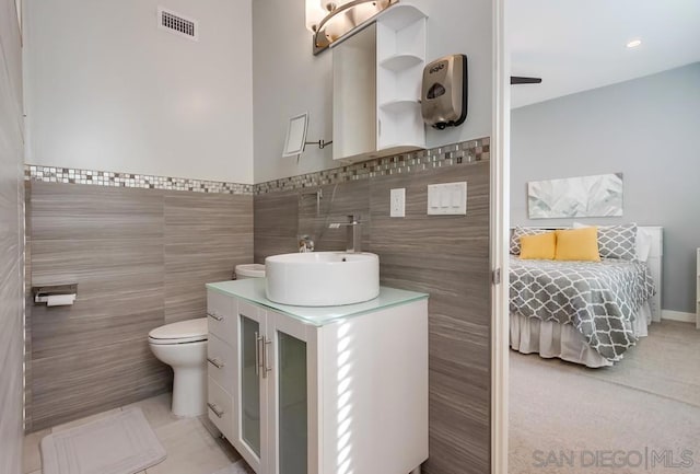 bathroom featuring tile patterned floors, vanity, tile walls, and toilet