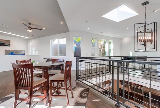 dining space with a skylight, ceiling fan with notable chandelier, and hardwood / wood-style flooring