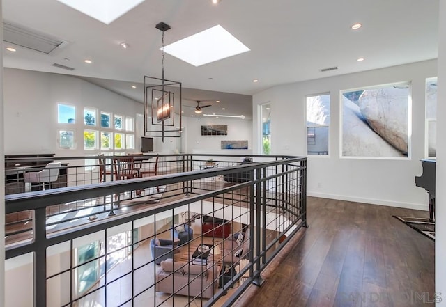 hallway featuring wood-type flooring, a skylight, plenty of natural light, and a notable chandelier