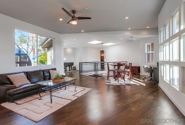 living room with a skylight, dark hardwood / wood-style floors, and ceiling fan