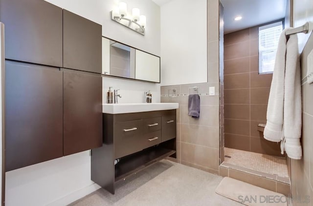 bathroom featuring vanity, tile walls, and tiled shower