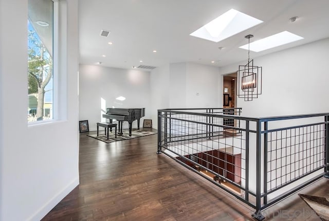 hallway with a notable chandelier, dark hardwood / wood-style floors, and a skylight