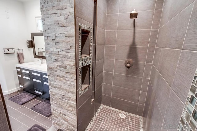 bathroom with a tile shower and vanity