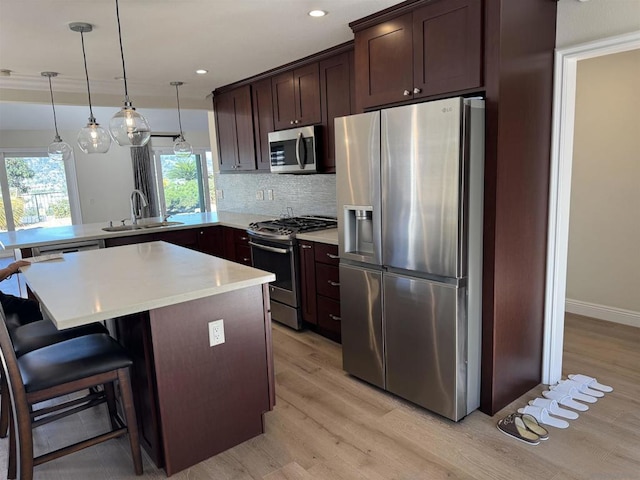 kitchen featuring sink, kitchen peninsula, decorative backsplash, appliances with stainless steel finishes, and light wood-type flooring