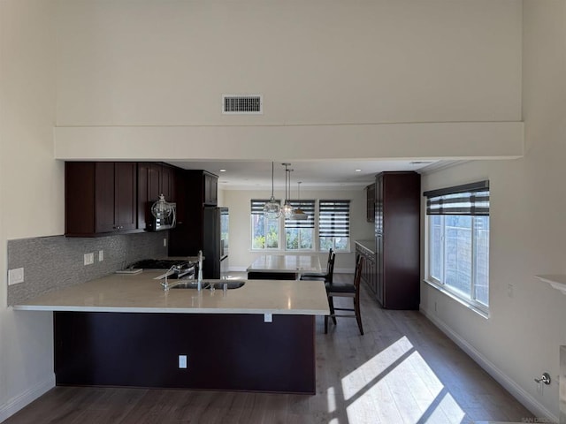 kitchen with a kitchen bar, appliances with stainless steel finishes, sink, decorative light fixtures, and light hardwood / wood-style flooring