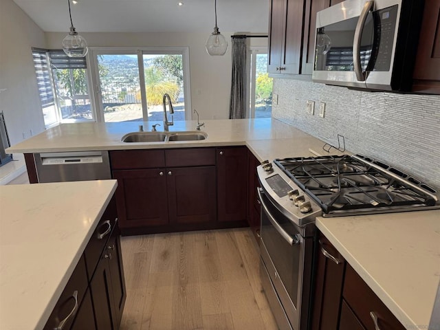 kitchen with stainless steel appliances, hanging light fixtures, light hardwood / wood-style floors, and sink