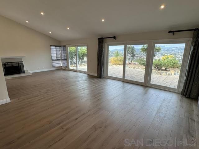 unfurnished living room featuring hardwood / wood-style flooring and lofted ceiling