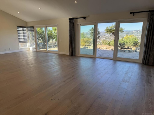 spare room with hardwood / wood-style flooring and vaulted ceiling