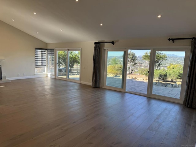 unfurnished living room featuring hardwood / wood-style flooring, vaulted ceiling, and a wealth of natural light