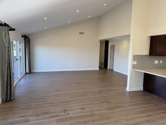 unfurnished living room featuring light wood-type flooring and high vaulted ceiling