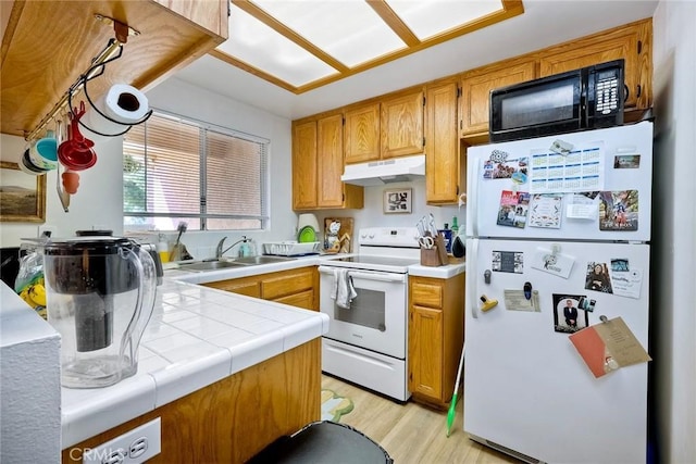 kitchen featuring tile counters, sink, white appliances, and light hardwood / wood-style floors